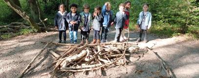 Les élèves se retrouvent autour de leur création dans la forêt.